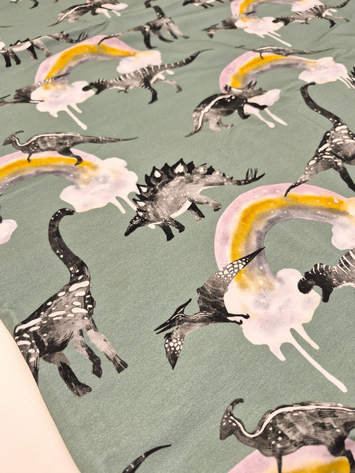 Pattern of dinosaurs and rainbows on a green background